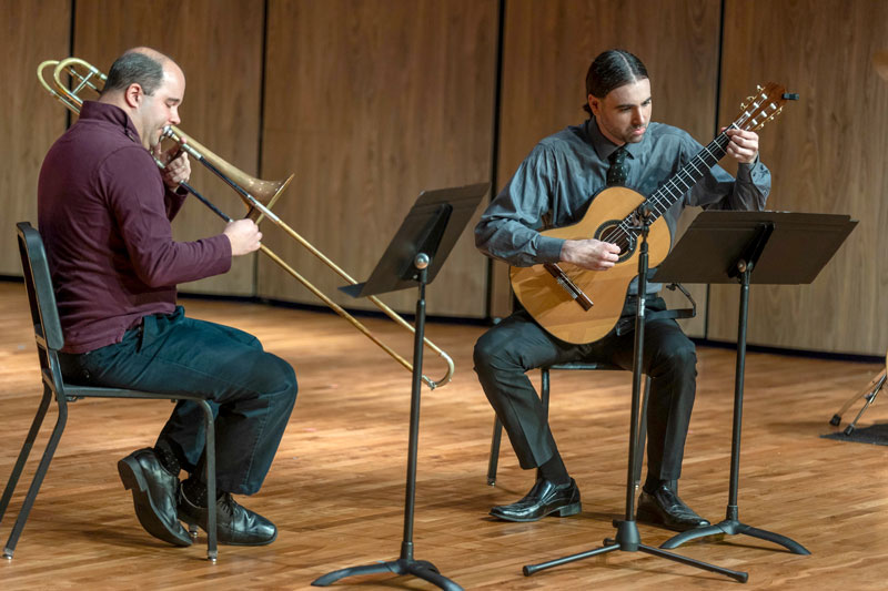 Photo of LCCC Music Faculty playing on stage with a trambone and guitar