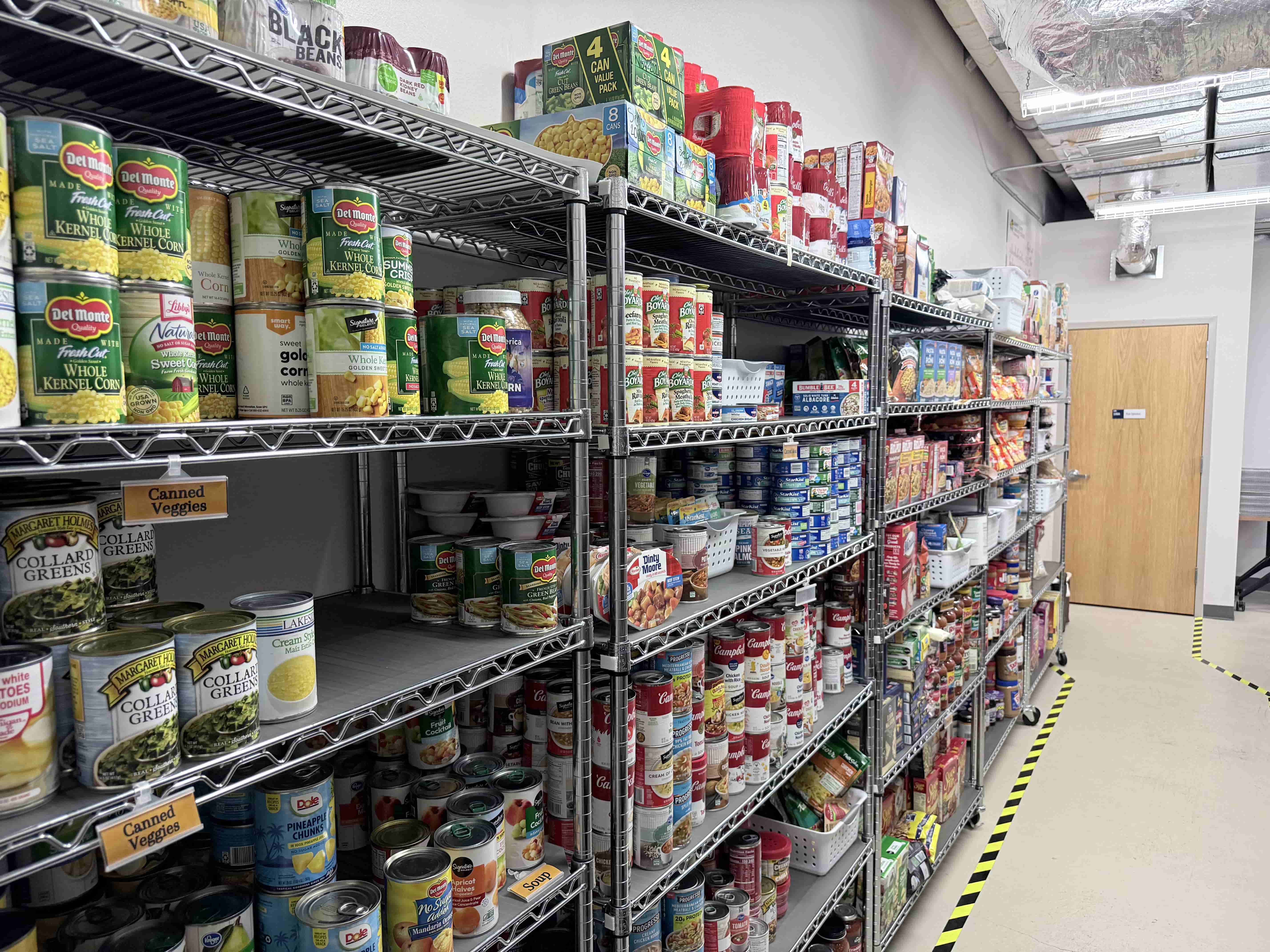 Shelves stocked with canned goods and pantry items inside the student food pantry.