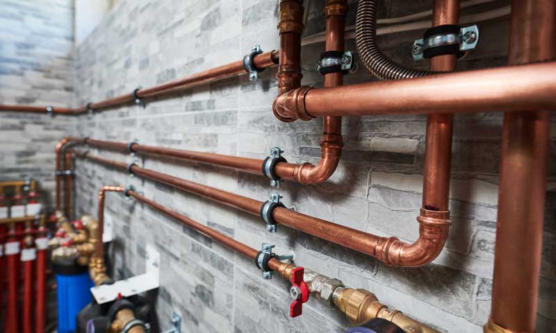 image of copper pipes along a wall