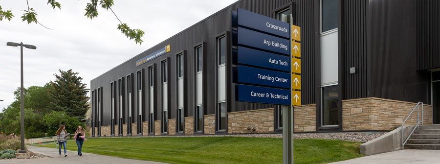 students walking near the Business Building which has had exterior work done on the concrete to insulate, seal and enhance it.