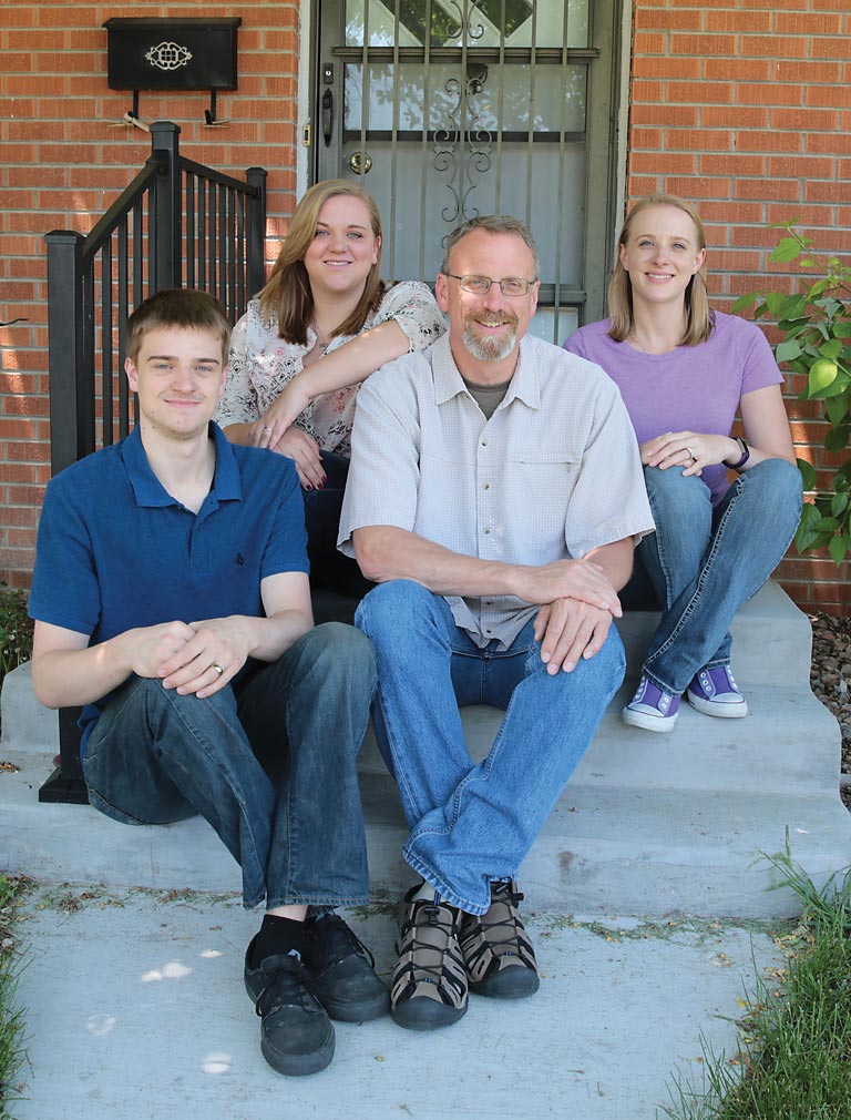 Doug McGee and family sitting on front step of house
