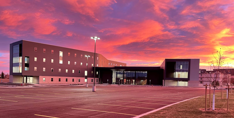 exterior of the new residence hall in the evening with a colorful sunset