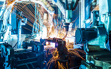 photo of machine arm welding with sparks flying