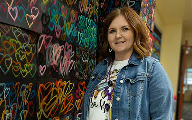 Lindsey Belmonte standing in front of heart artwork
