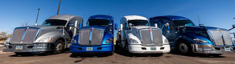 Line of four Semi Trucks in a parking lot