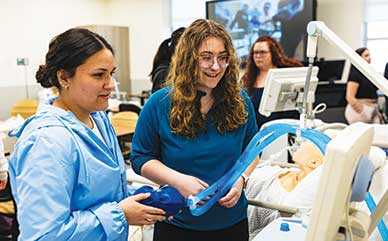 two students holding a breathing tube and looking at a screen