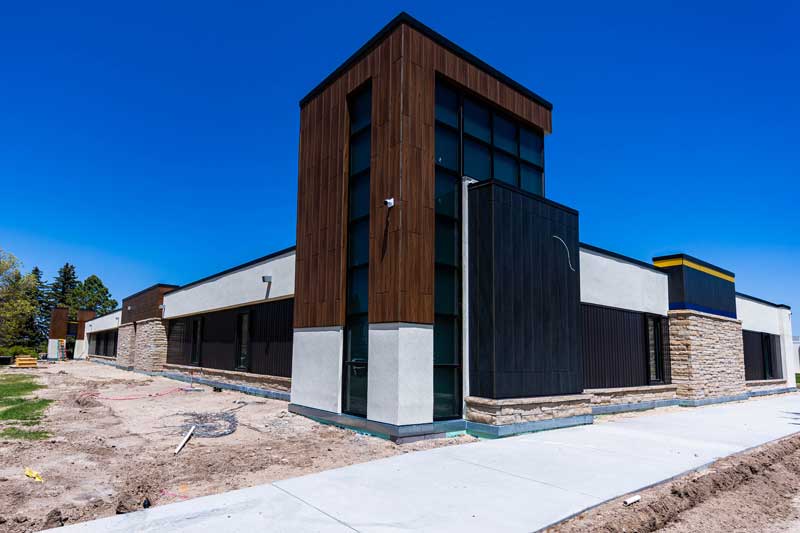Corner of the CCI Building visible from the road almost finished with construction with wood, metal and stone finishes.