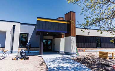 Exterior of the CCI building under construction with workers and equipment by the entrance door