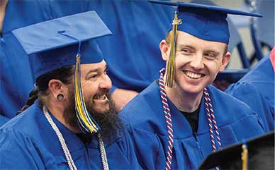 two LCCC graduates at the commencement ceremony in caps and gowns smiling