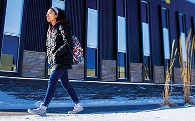 a student walking in front of the Business Building on campus