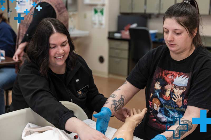 faculty member and student in a Health Sciences lab classroom with gloves on