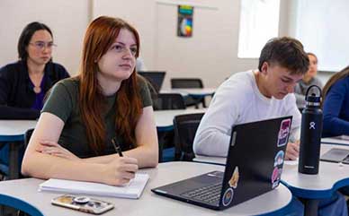 students in class sitting at tables with notes in front of them