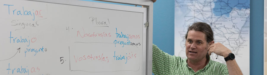 Ian Caldon teaching class with a white board with Spanish words written on it.