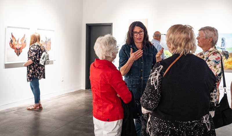 June Glasson speaking with people in the gallery during her reception