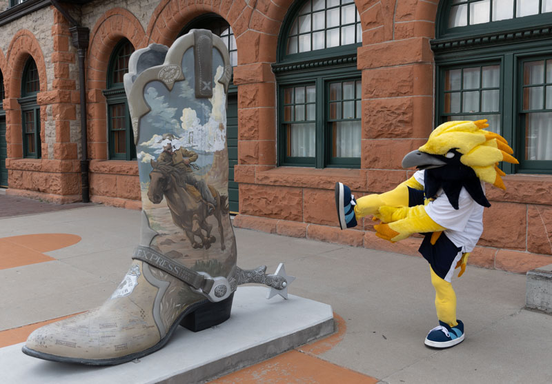 Talon the mascot in downtown Cheyenne by a boot scuplture