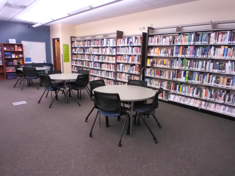 3 tables with chairs and wall of books in library