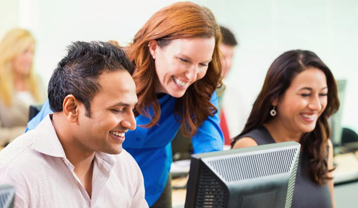 woman teaching two others at computers