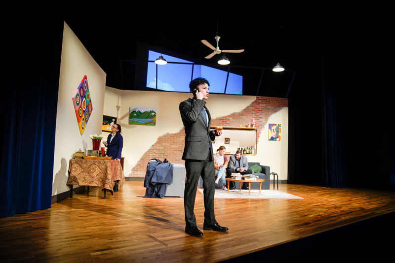 LCCC student standing on stage in a suit during a play