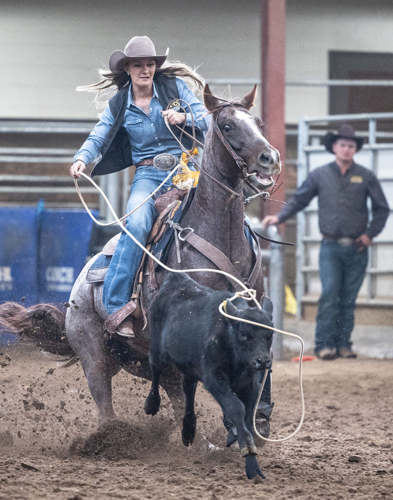 female rodeo student roping from a horse during a rodeo event