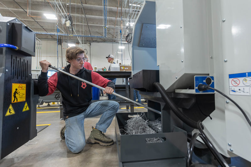 AMMC student cleaning out the metal scraps from a machine