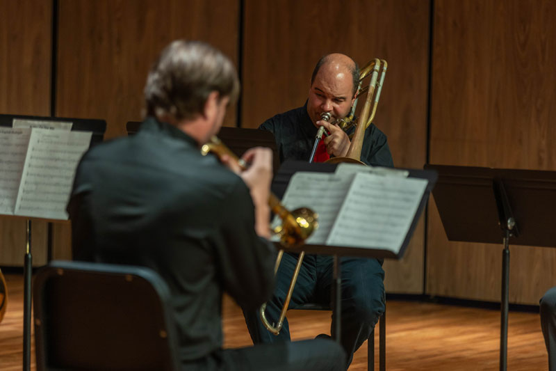 photo of music faculty playing trombones on stage during a concert