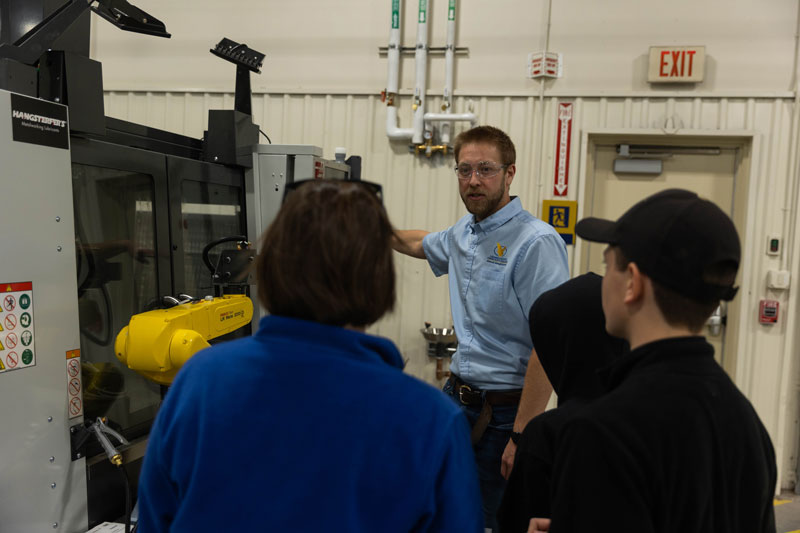 Photo of two people learning about machinery in the LCCC AMMC from an employee