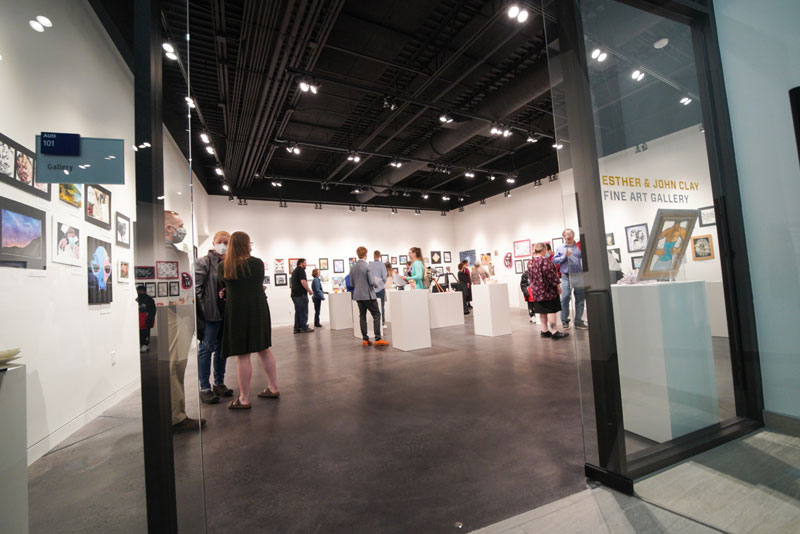 Photo of the LCCC art gallery with the LCCC student art show up and people looking at the show.