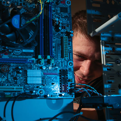 student looking at back of computer with wires