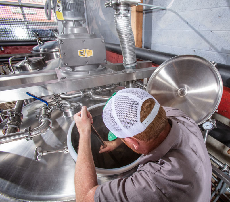 owner of Bonds Brewing stirring while making craft beer