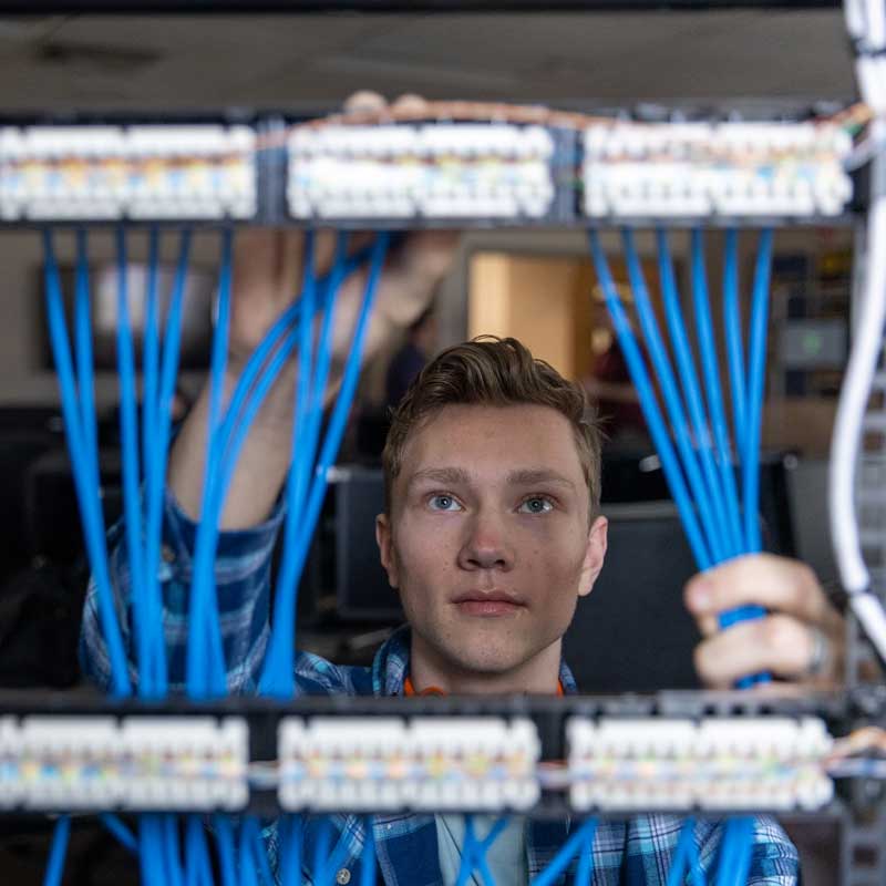 Student looking through many computer cables hooked up to computer components