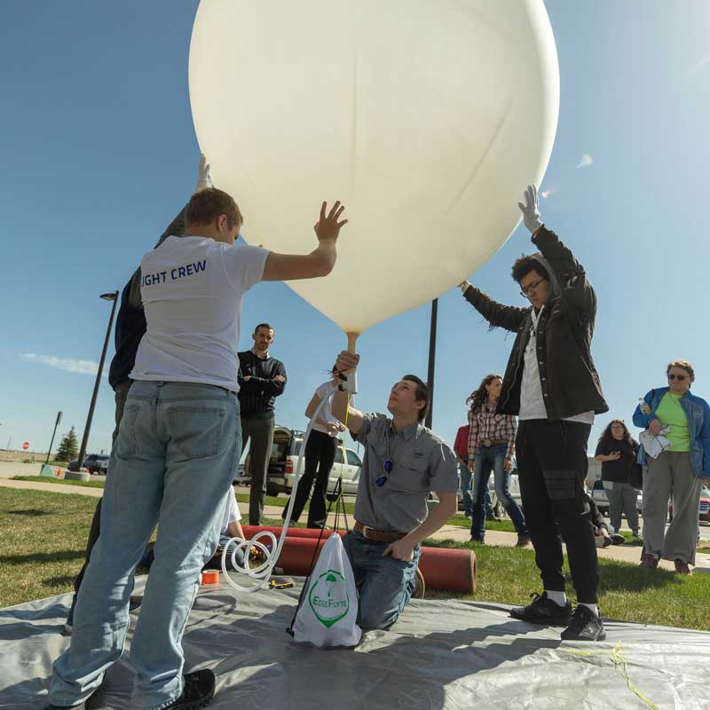 a group of students holding a giant weather balloon ready to be released