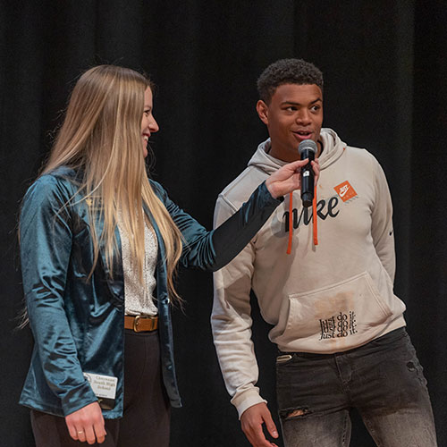 a high school student talking into a microphone at a signing day