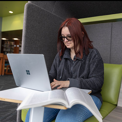 a student working at a laptop in the library