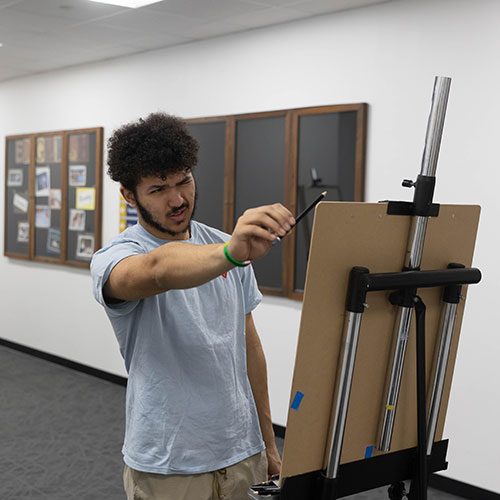 Student in art class drawing at an easel.