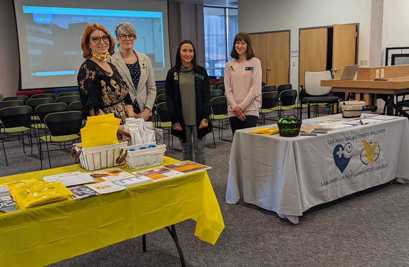 Photograph of two members of Grace for 2 Brothers and LCCC Counseling staff stand near tables with information about mental health topics in the LCCC Student Lounge