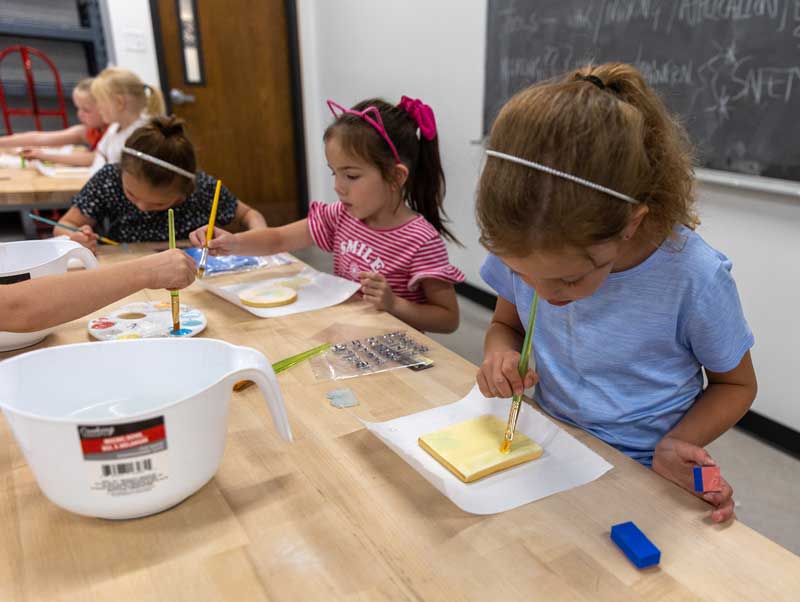 CDC students painting in the ceramics studio on campus at tables