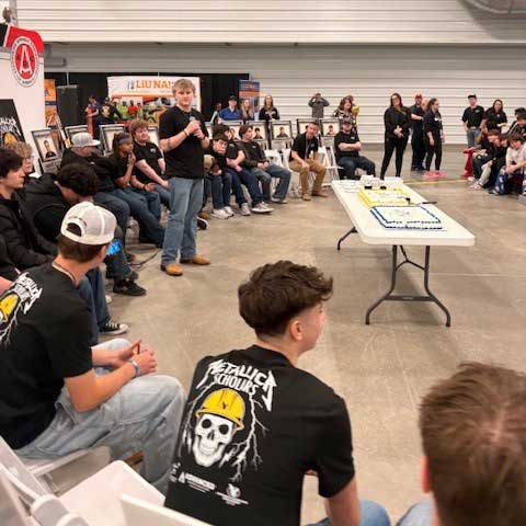 large group of students in Metallica Scholars t-shirts listening to one speak at the Metallica Scholars kick-off event